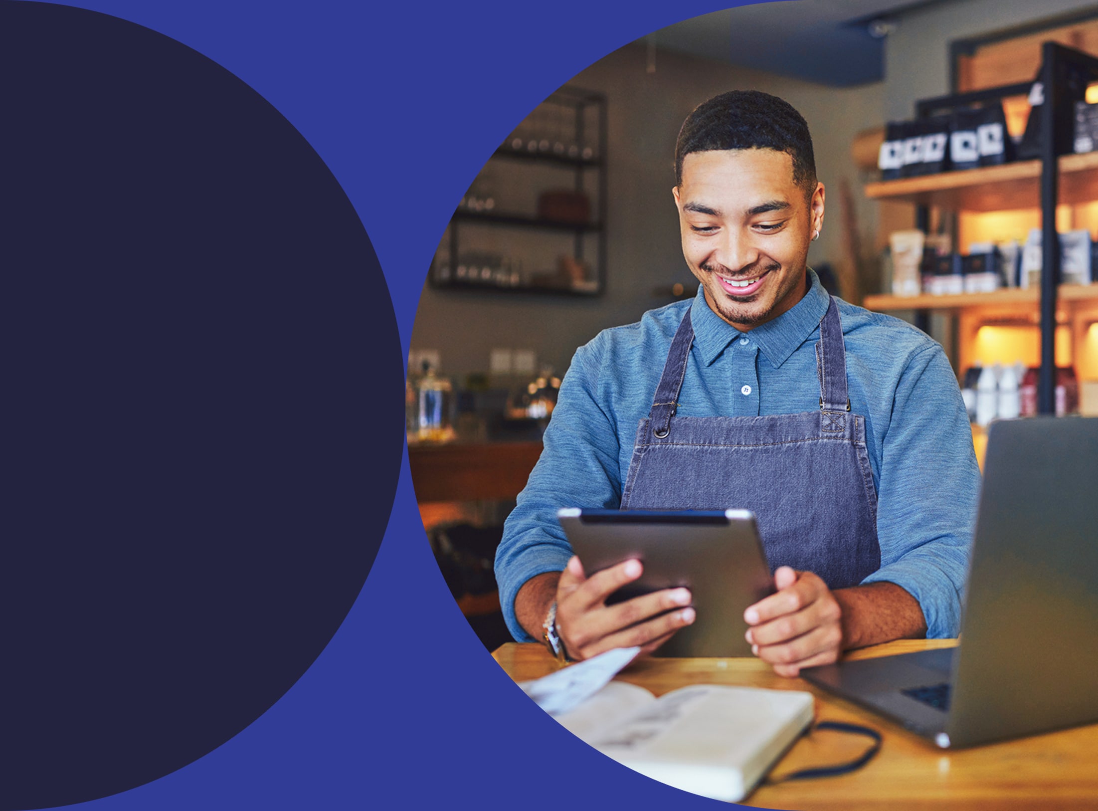 Smiling business owner managing his business with tablet and laptop